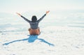 Happy woman sits on the snowy mountain hill over the city. Sunny