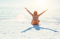 Happy woman sits on the snowy mountain hill over the city. Sunny