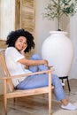 happy woman sitting on armchair and looking at camera Royalty Free Stock Photo