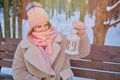 A happy woman is sitting on a bench with a lantern in her hands, a winter park with snow-covered trees Royalty Free Stock Photo