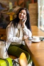 Happy woman sitting at cafe waiting departure flight in airport terminal talking use smartphone Royalty Free Stock Photo