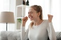 Happy woman sitting on couch celebrate good news