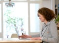 Happy woman sitting at desk using laptop at home Royalty Free Stock Photo