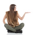 Happy Woman Sitting On Floor Presenting And Looking Away Royalty Free Stock Photo