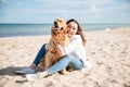 Happy woman sitting and hugging her dog on the beach Royalty Free Stock Photo