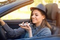 Happy woman sitting inside convertible car using a smart phone voice recognition function on line Royalty Free Stock Photo