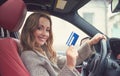 Happy woman sitting inside her new car showing credit card Royalty Free Stock Photo
