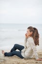 Happy woman sitting on lonely beach and talking cell phone Royalty Free Stock Photo