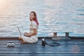 Happy woman sitting in pier with laptop. Freelance job or distance learning idea. Work while travel concept, copy space