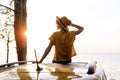 Happy Woman Sitting on Yellow Car Roof at Sunset