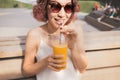 Woman with slim figure drinks freshly squeezed orange juice from a plastic cup. Useful and harmful beverages