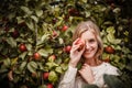 Happy woman smiling and having fun with apples. Hiding one eye behind freshly picked apple.