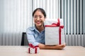 Happy woman is smiling and holding big present box with red ribbon in the hands while preparing gift for celebrate Royalty Free Stock Photo