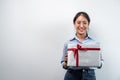 Happy woman is smiling and holding big present box with red ribbon in the hands while standing to preparing gift Royalty Free Stock Photo