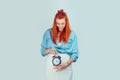 Happy woman smiling holding a clock at big pregnant belly Royalty Free Stock Photo