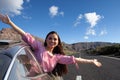 Happy woman smiling and holding hands outside open window car against road and mountain background. Royalty Free Stock Photo