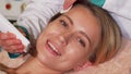 Happy woman smiling to the camera while getting ultrasonic facial treatment