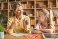 Happy woman speech therapist teaching little girl with pronounciation deffects to say sound R during personal training