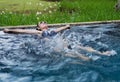 Happy woman splashing water by leg in swimming pool Royalty Free Stock Photo