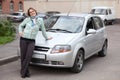Happy woman standing in front of own car