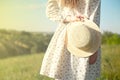 Happy woman standing with her back at the edge of a mountain cliff at sunset light sky holding a straw hat Royalty Free Stock Photo