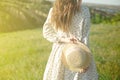 Happy woman standing with her back at the edge of a mountain cliff at sunset light sky holding a straw hat Royalty Free Stock Photo