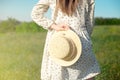 Happy woman standing with her back at the edge of a mountain cliff at sunset light sky holding a straw hat Royalty Free Stock Photo