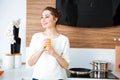 Happy woman standing on kitchen and drinking orange juice Royalty Free Stock Photo