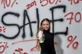 Happy woman standing near wall with sale inscription