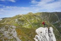 Happy woman standing on one leg on a cliff in the mountains