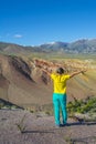 Happy woman standing on rock with raised hands at mountain peak