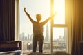 Happy woman stretches and opens curtains at window in morning