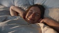 Happy woman stretching bed in sunlight closeup. Carefree smiling girl waking up Royalty Free Stock Photo