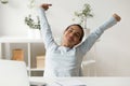 Happy woman stretching in front of desk at work Royalty Free Stock Photo