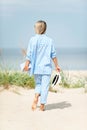 Happy woman with summer hat holding book walking on seaside sand Royalty Free Stock Photo