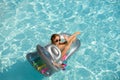 Happy woman in swimmsuit. Girl on summer vacation. Female in swimmingpool on inflatable mattress.