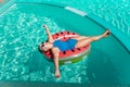 Happy woman in a swimsuit and sunglasses floating on an inflatable ring in the form of a watermelon, in the pool during
