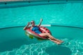 Happy woman in a swimsuit and sunglasses floating on an inflatable ring in the form of a watermelon, in the pool during