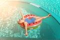 Happy woman in a swimsuit and sunglasses floating on an inflatable ring in the form of a watermelon, in the pool during