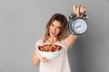 Happy woman in t-shirt showing healthy food and alarm clock Royalty Free Stock Photo