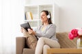 Happy woman with tablet pc and headphones at home Royalty Free Stock Photo