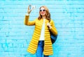 Happy woman takes a picture self portrait on smartphone on brick Royalty Free Stock Photo