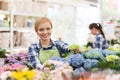 Happy woman taking care of flowers in greenhouse Royalty Free Stock Photo