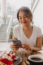 Happy woman taking photo of her cake in the cafe before eat. Royalty Free Stock Photo