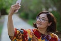 Happy woman taking a selfie with her mobile phone in a blooming park Royalty Free Stock Photo