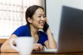 Happy woman talking on cell phone with open laptop on table work at home concept. Royalty Free Stock Photo