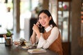 Happy woman talking on mobile phone and looking at camera while siting in modern coffee shop. Royalty Free Stock Photo