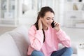 Happy woman talking on mobile phone sitting on comfortable couch Royalty Free Stock Photo