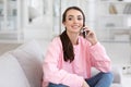 Happy woman talking on mobile phone sitting on comfortable couch Royalty Free Stock Photo