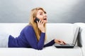 Happy woman talking on mobile phone and using laptop lying on sofa, modern technology Royalty Free Stock Photo